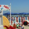 Area giochi per bambini sulla spiaggia, con ombrelloni blu.