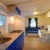 Interno cucina con mobili blu, tavolo da pranzo e divano vicino a finestre con tende.