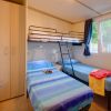 Camera con letto singolo, letto a castello, armadio e finestra. Copriletto blu e giochi sul letto.