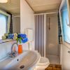 Bagno con lavandino, doccia, WC, finestra e asciugamani colorati vicino al lavandino.