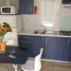 Cucina compatta con lavandino, fornelli, microonde e vaso di girasoli sul tavolo.