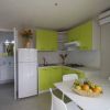 Cucina moderna con mobili verdi e frutta sul tavolo.