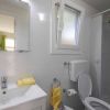 Bagno con wc, lavabo, specchio e asciugamani gialli. Finestre e doccia presenti.
