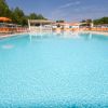 Piscina vuota con sdraio e ombrelloni sullo sfondo.