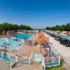 Piscine all'aperto con ombrelloni arancioni, persone che nuotano e relax.