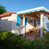 Un bungalow con persiane blu e veranda coperta, circondato da piante.