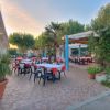 Un ristorante all'aperto con tavoli apparecchiati e sedie sotto pergolati.