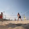 Persone che giocano a beach volley su una spiaggia sabbiosa.