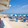 Lettini e ombrelloni blu su spiaggia assolata.
