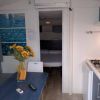 Interno di un bungalow con cucina, tavolo blu, sedia, e un vaso di fiori gialli su un tavolo.