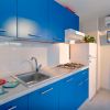 Cucina con mobili blu, lavello inox, fornello a gas, frigo bianco, aria condizionata e TV.