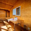 Veranda in legno con tavolo, panche e finestre azzurre.