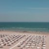 Spiaggia sabbiosa con ombrelloni e mare.