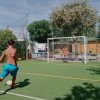 Ragazzo calcia un pallone verso la porta in un campetto.