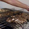 Mani che sistemano una griglia sopra il barbecue.