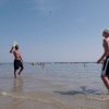 Due persone giocano a palla in acqua sulla spiaggia.