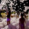 Bambini che giocano tra la schiuma di notte.