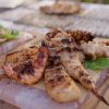 Piatti di pesce grigliato su tavole di legno.
