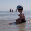 Bambino seduto in acqua bassa al mare.