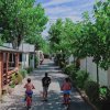Tre bambini in bicicletta su una strada alberata.
